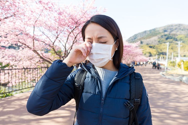 woman in mask scratching eyes